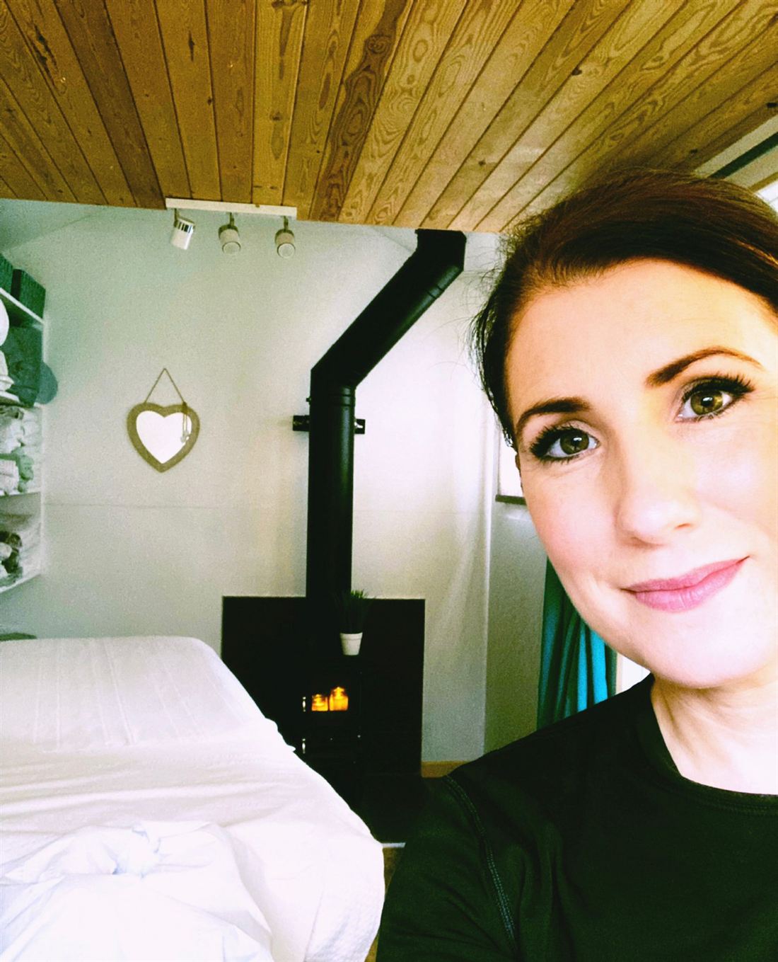 Harriet in the Beauty Culture treatment cabin, with its wooden ceiling, log burner and treatment bed